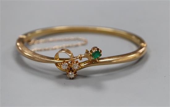 A diamond and emerald four stone set 15ct hinged bangle.